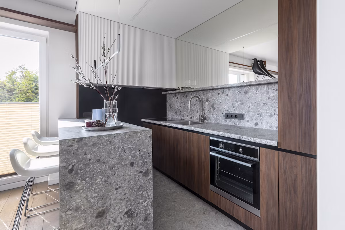 Compact luxury kitchen with dark cabinetry, stone worktops and warm timber details
